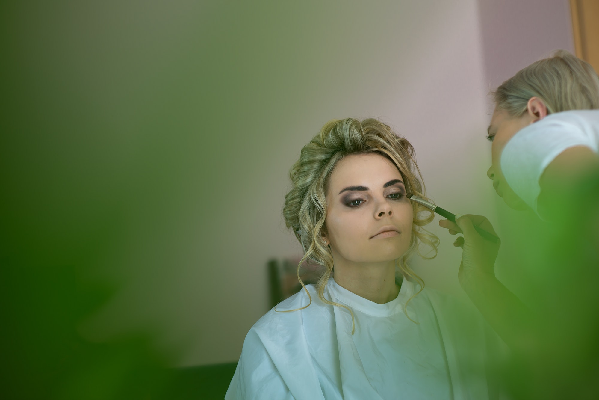 makeup artist preparing bride before the wedding in a morning