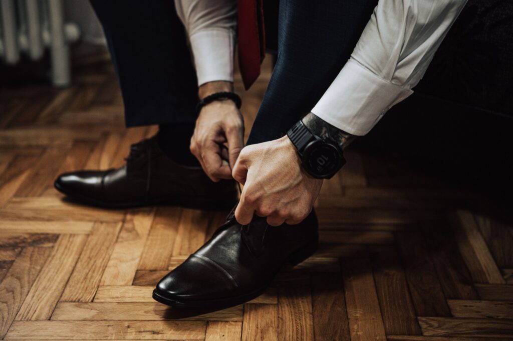 Groom getting ready and lacing up his shoes