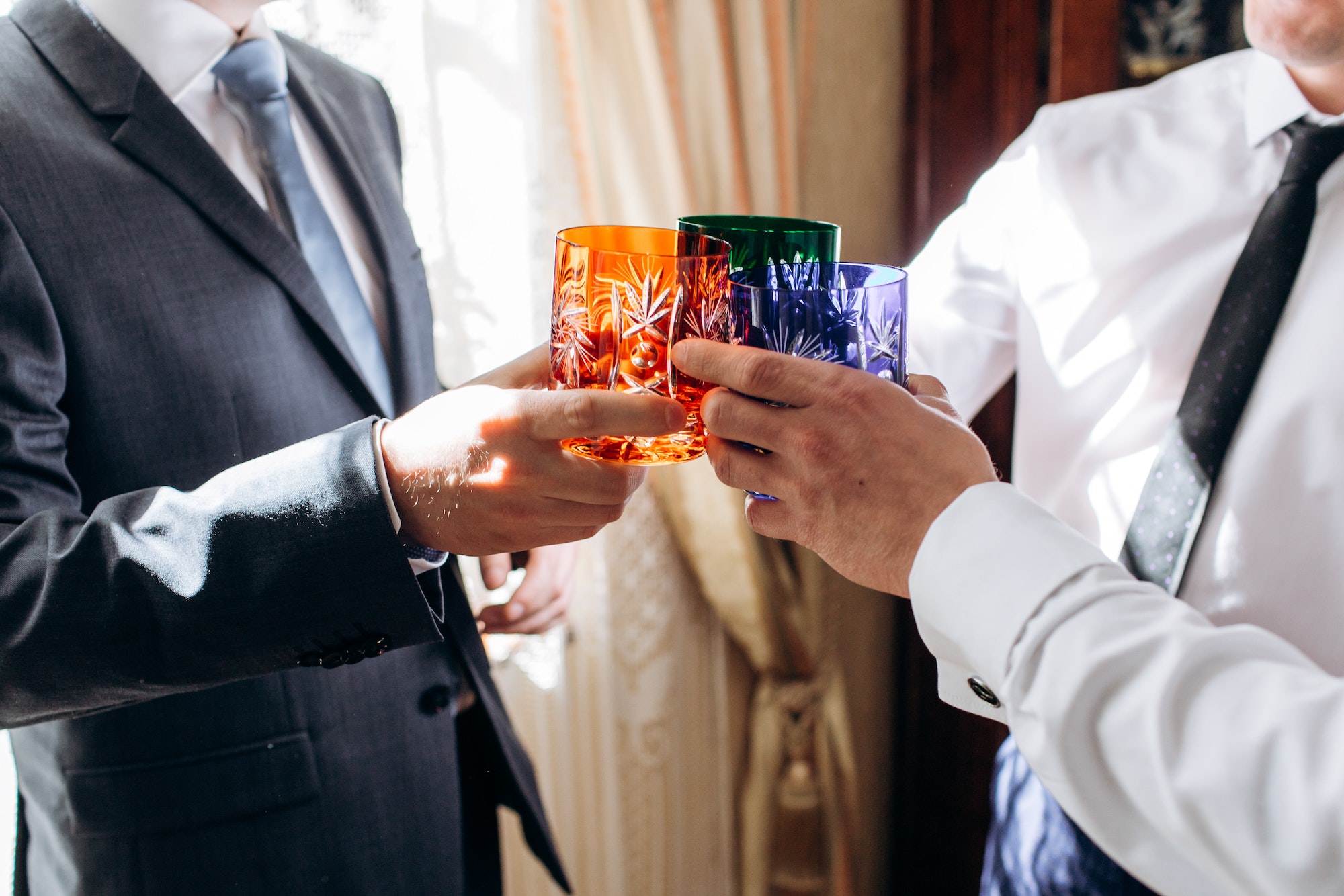 men hands holding colorful cups and toasting